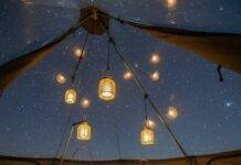 Glamping, But Make It Green: Top Eco Glamping Spots in the U.S. Tent view: grass, starry mesh roof, dangling lanterns.
