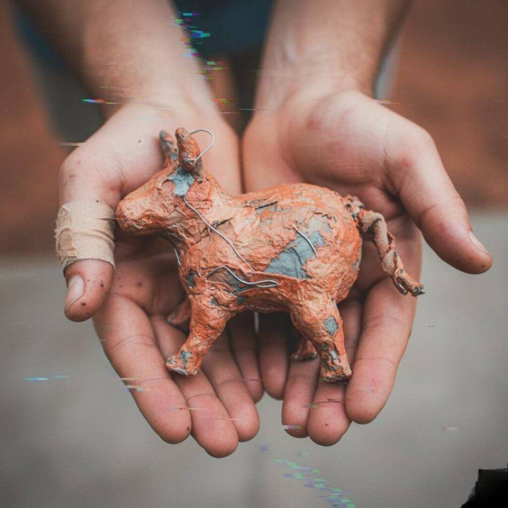 Blistered hands holding wonky artifact with digital glitches.