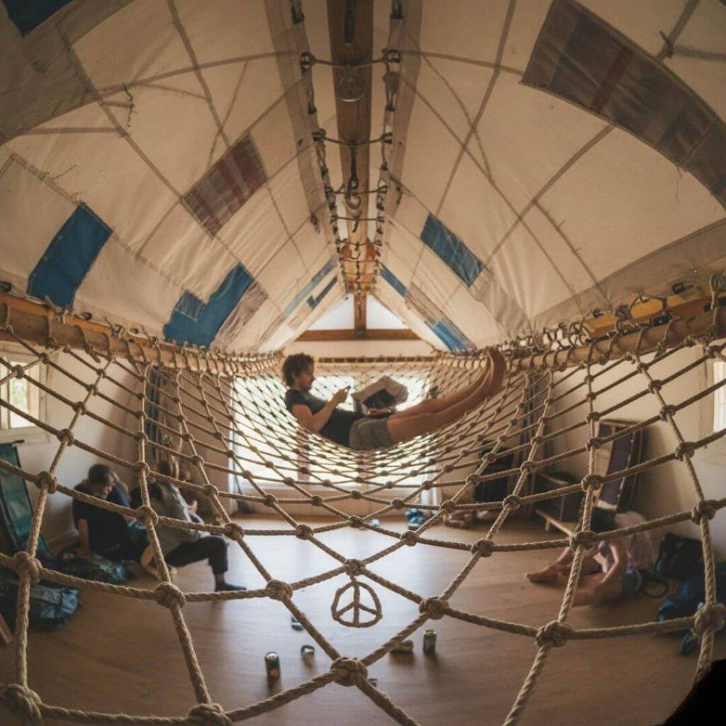 Hammock net, recycled sails, person relaxing, peace sign.