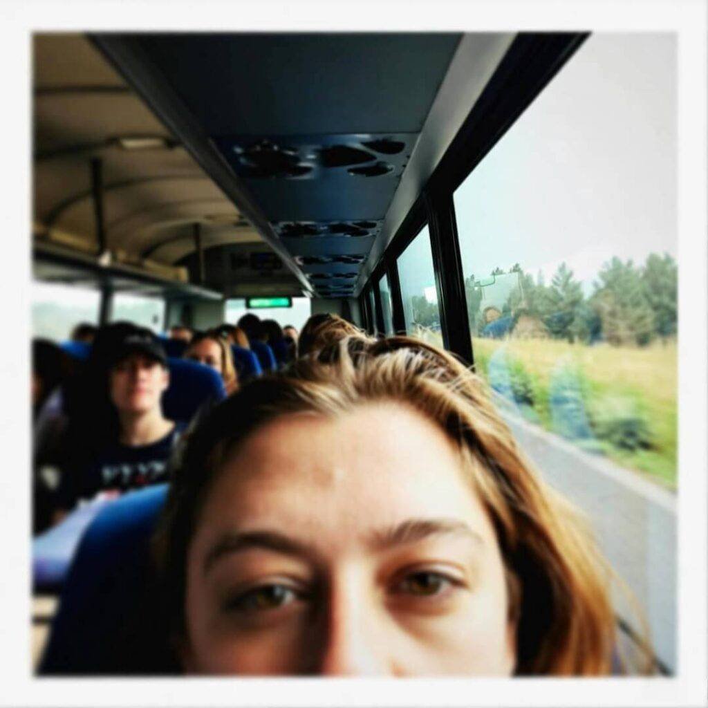 Tired face on bus with farmland view.