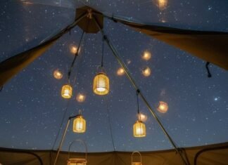 Glamping, But Make It Green: Top Eco Glamping Spots in the U.S. Tent view: grass, starry mesh roof, dangling lanterns.